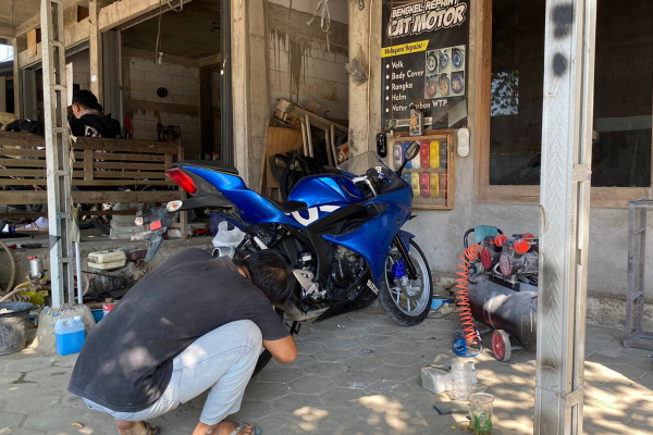 Agus Pribadi Waluyo, tengah melakukan perbaikan body motor.